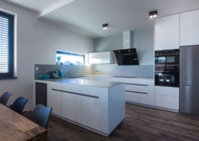 Luxusní designová bílá kuchyň, keramická deska v dekoru beton, ostatní nábytek